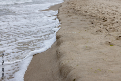 Fototapeta Naklejka Na Ścianę i Meble -  Picturesque view of the sandy beach of the Baltic Sea, foamy water flowing into the sand, Miedzyzdroje, Poland