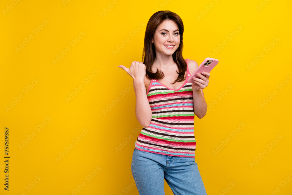 Portrait of smart woman with piercing wear tank hold smartphone directing at offer empty space isolated on vivid yellow color background Portrait of smart woman with piercing wear tank hold smartphone directing at offer empty space isolated on vivid yellow color background