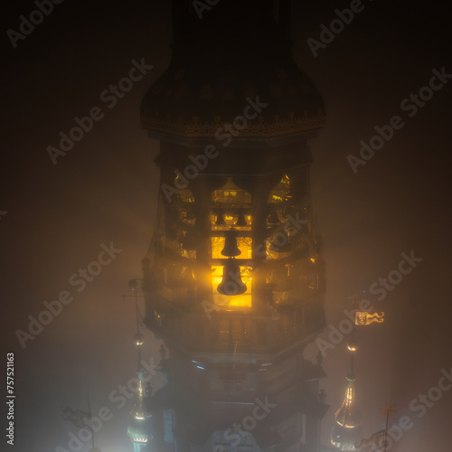 Illuminated bells on the tower of Main Town Hall in Gdansk at foggy night. Poland