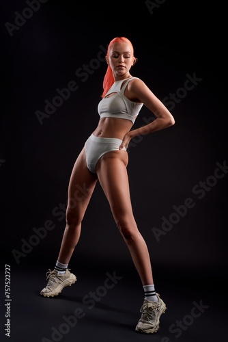 Sporty sexy woman in underwear standing in dark studio