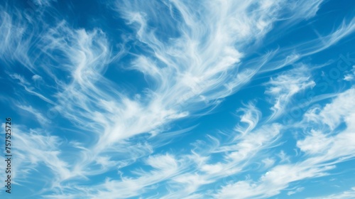Wispy white clouds stretch across the bright blue sky. The clouds are illuminated by the sun  which is not visible in the frame.