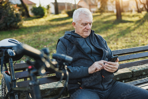 Man Sitting on Bench Using Cell Phone in a Park