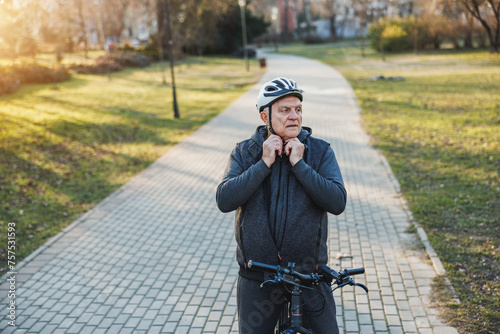 A senior man standing upright next to a bicycle with a protective helmet ready to begin a safe ride or has just finished one.