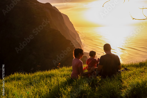 Family with child on meadow watching breathtaking sunset at viewing point Miradouro do Ponta da Ladeira, Madeira island, Portugal, Europe. Panoramic view of majestic coastline of Atlantic Ocean. Awe photo