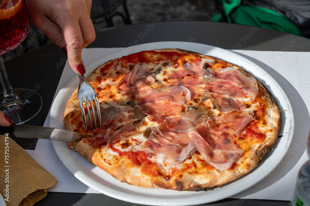 Eating of fresh baked pizza dish in italian pizzeria restaurant, Prosciutto di Parma Eating of fresh baked pizza dish in italian pizzeria restaurant, Prosciutto di Parma