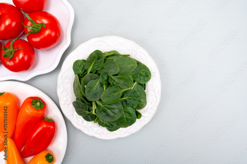 Fresh tomatoes, paprika, green Spinach leaves, diet and health concept, weight loss, spinach on ceramic plate, copy space Fresh tomatoes, paprika, green Spinach leaves, diet and health concept, weight loss, spinach on ceramic plate, copy space