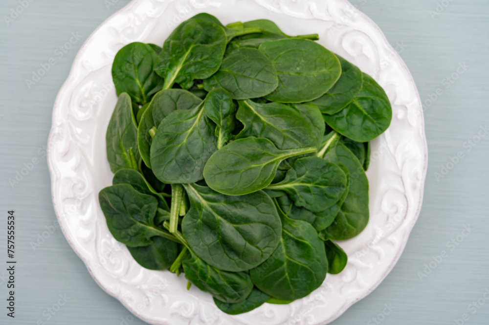 Fresh green baby Spinach leaves, diet and health concept, weight loss, spinach on ceramic plate, copy space Fresh green baby Spinach leaves, diet and health concept, weight loss, spinach on ceramic plate, copy space