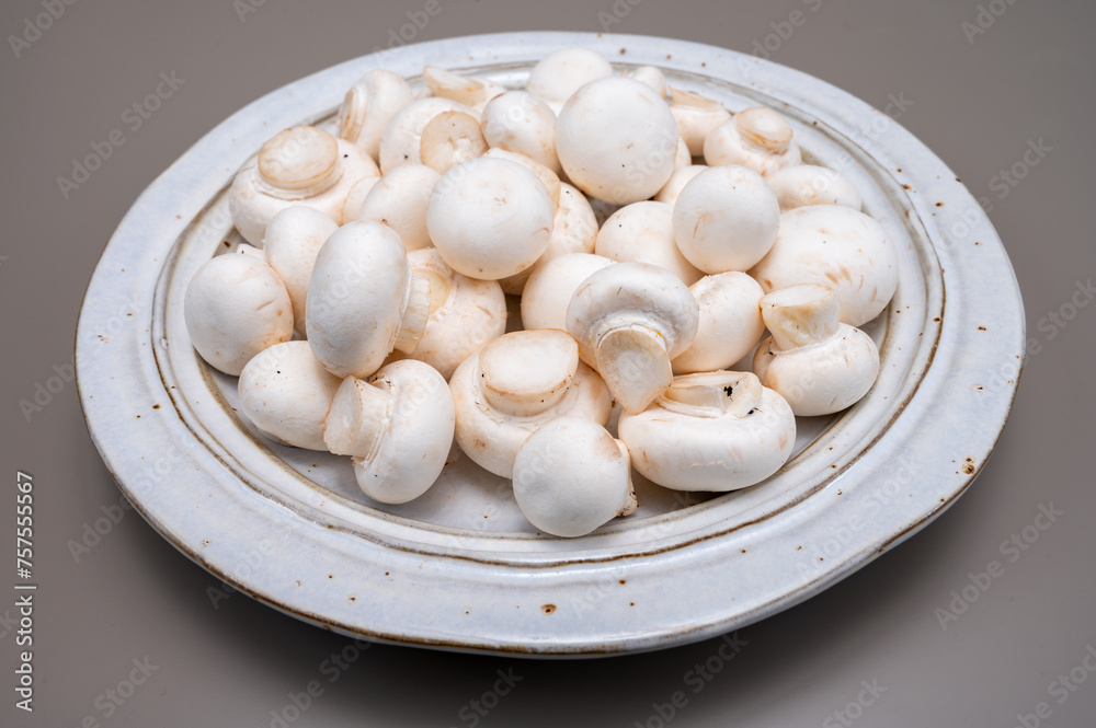 White champignon mushrooms fresh uncooked on white ceramic plate copy space White champignon mushrooms fresh uncooked on white ceramic plate copy space