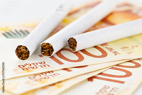 Cigarettes are on 100 shekel bills. Concept of big expenses, big price or taxes.
