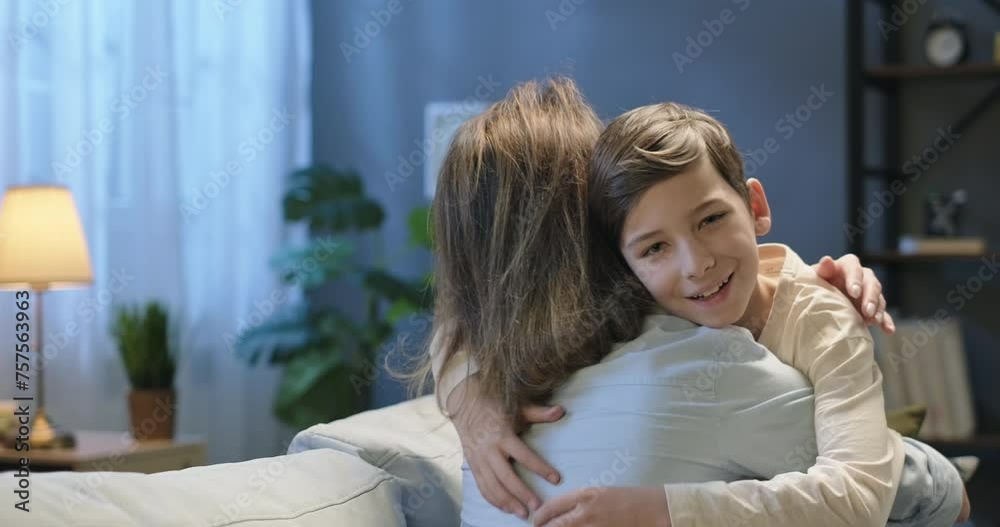 Happy kid boy hugs embraces cuddle his mother and looking into the camera. Tender moments feelings. Mother's Day concept Happy kid boy hugs embraces cuddle his mother and looking into the camera. Tender moments feelings. Mother's Day concept