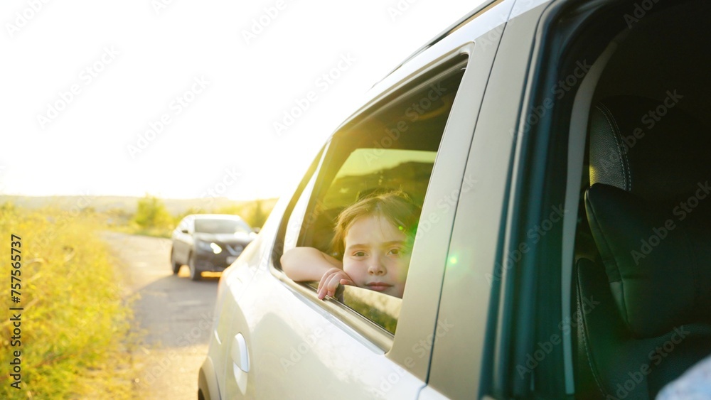 child girl face looks smiling from car out window, enjoying summer freedom during trip, trip, hand, summer time, catches wind with his hand from car window, children dream, car driving time, car