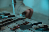 Weapons on the table. Kidnapped woman sitting on a chair and tied with a rope. Crime, kidnapping, violence concept
