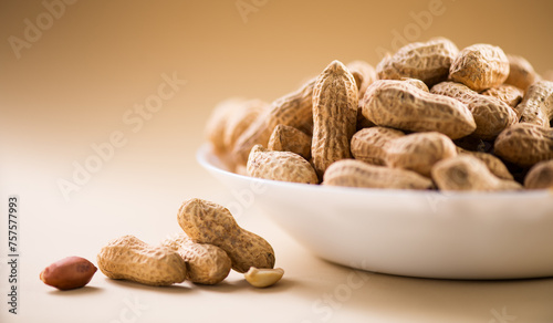 Peanuts. Unshelled nuts in a bowl close up. Roasted pile of peanuts in shell over beige background. Organic vegan, vegetarian food. Healthy nutrition concept. © Subbotina Anna
