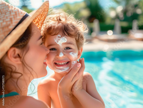 A young mother applies protective sunscreen to her son's face on the beach. A woman's hand applies sunscreen lotion to a child's face against the background of blue sea water or a swimming pool