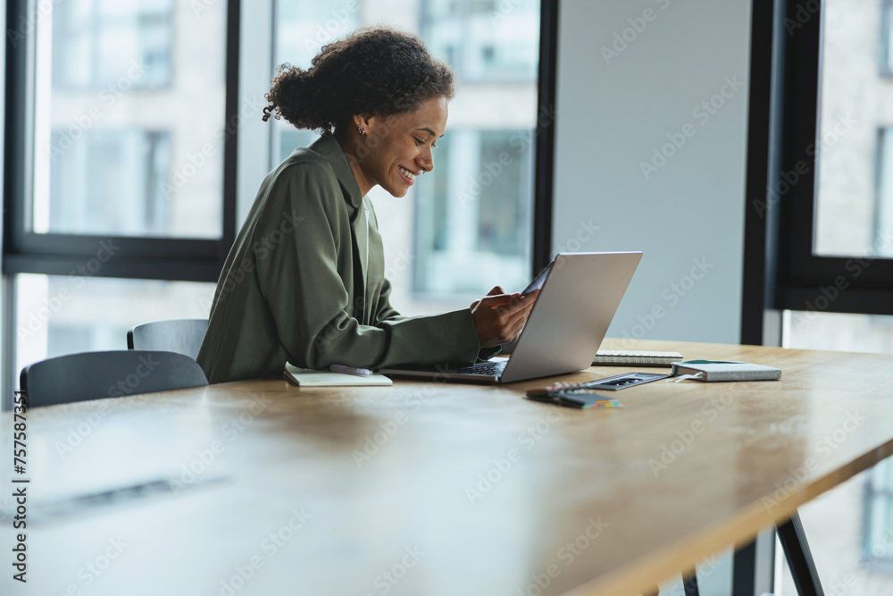 A woman sits at a table using a laptop computer in a building interior A woman sits at a table using a laptop computer in a building interior