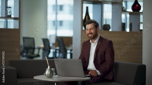 Smiling worker speaking virtual meeting with colleagues remotely at coworking