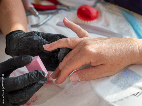 Manicure woman using polishing sponge removing old polish for permanent nail paint