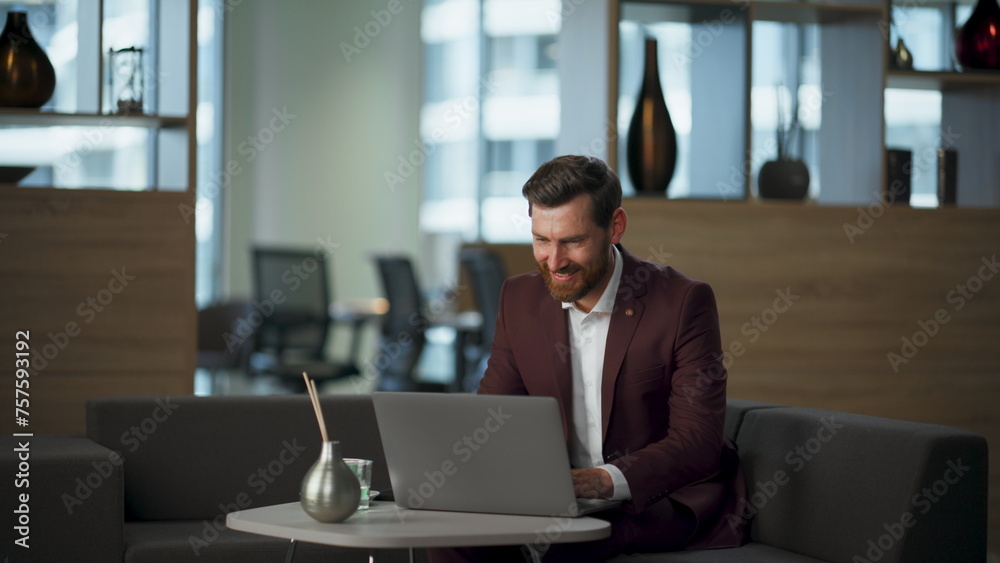 Happy worker looking computer in cozy office. Businessman rejoicing success Happy worker looking computer in cozy office. Businessman rejoicing success