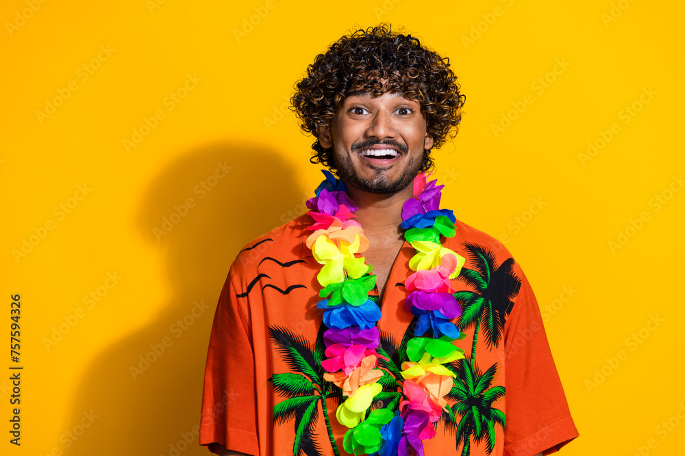 Portrait of cheerful guy with afro hairstyle wear hawaii flower necklace smiling on vacation isolated on vivid yellow color background