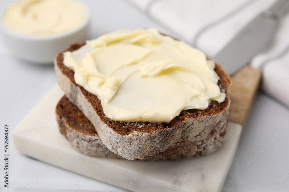 Slices of tasty bread with butter on white table, closeup Slices of tasty bread with butter on white table, closeup