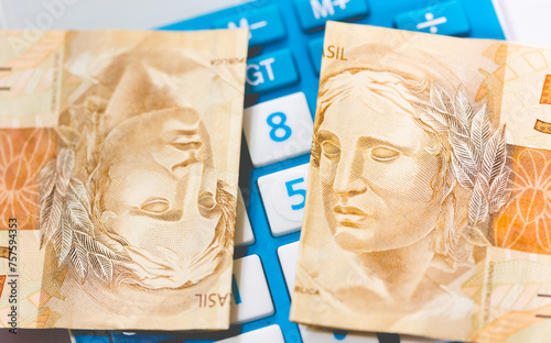 Cédulas do Real Brasileiro de 50 Reais sobre uma calculadora azul. Dinheiro, Brasil, Imposto de Renda. photo