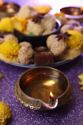 Diwali celebration. Diya lamp on shiny violet table  closeup