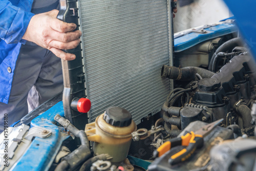 A man installs a new radiator in a car