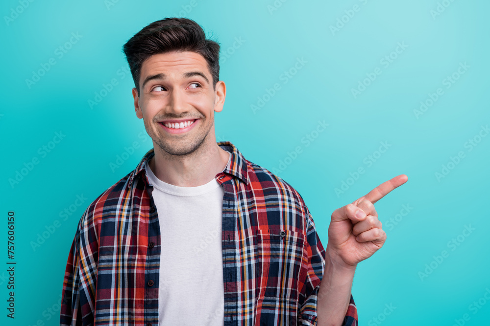Photo of excited dreamy man dressed plaid shirt looking pointing finger empty space isolated turquoise blue color background Photo of excited dreamy man dressed plaid shirt looking pointing finger empty space isolated turquoise blue color background