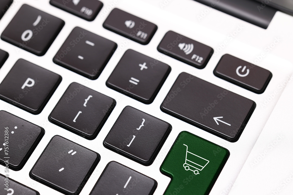 Internet store. Green button with shopping cart on computer keyboard, closeup