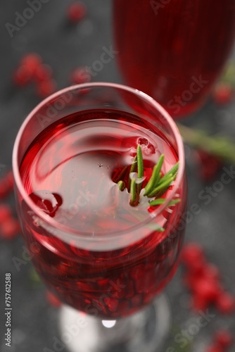 Tasty cranberry cocktail with rosemary in glass on gray table, closeup