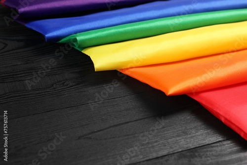 Rainbow LGBT flag on black wooden background, closeup. Space for text
