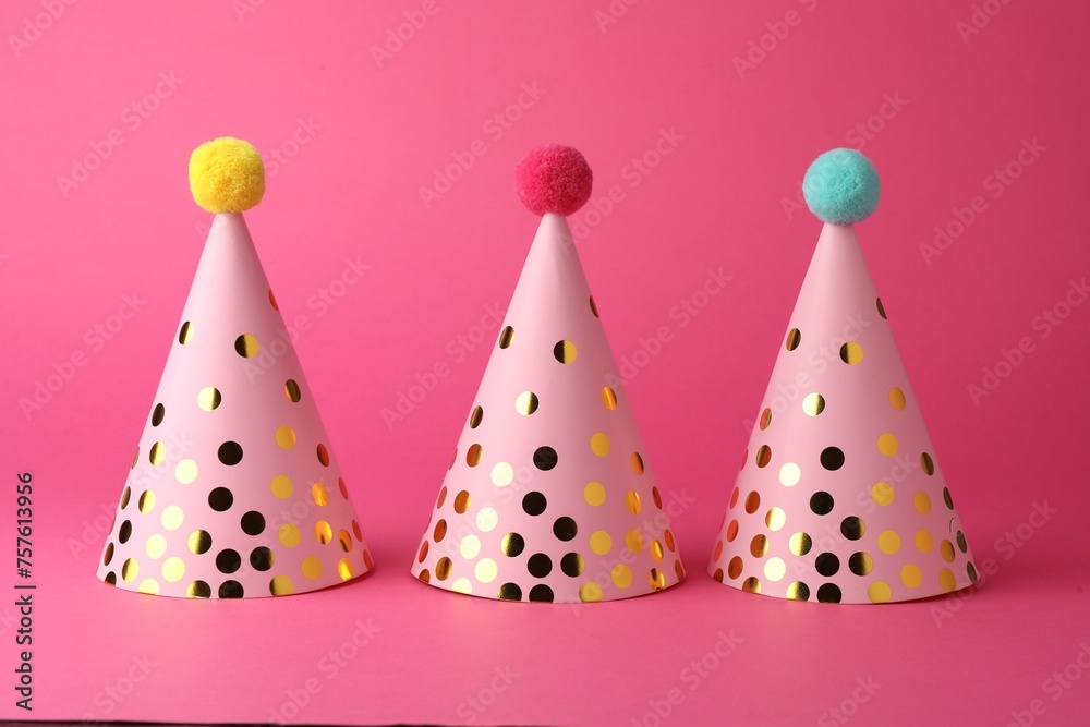 Beautiful party hats with pompoms on pink background Beautiful party hats with pompoms on pink background