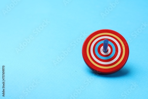 One colorful spinning top on light blue background, space for text