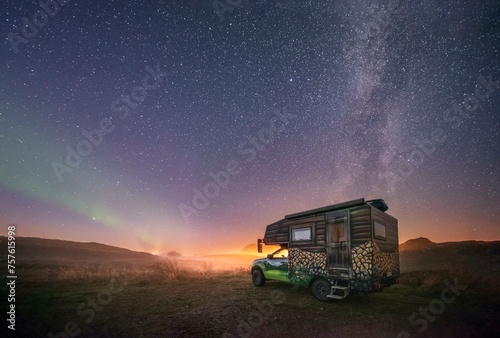 Night shot of a painted camper van under the Milky Way with northern lights, Gimsoy, Lofoten, Nordland, Norway, Europe photo