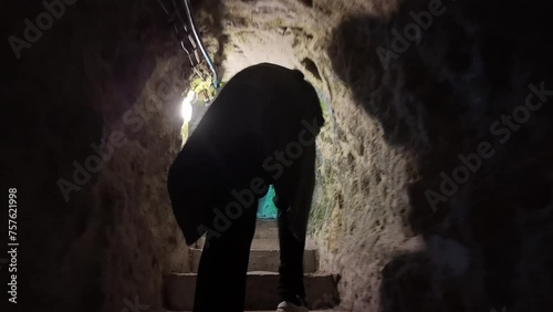 Female traveler walks in narrow tunnels of the Derinkuyu underground city built in BC 1200 in Cappadocia, Turkey.