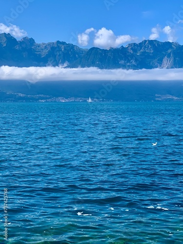 sea and sky. Sailboat. Lake and mountains. Clear alpine lake. Stone  rocks. Low clouds just above the water on a summer sunny day.