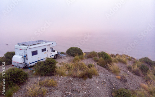 Caravan with solar panels on roof on coast, Spain. Aerial view.