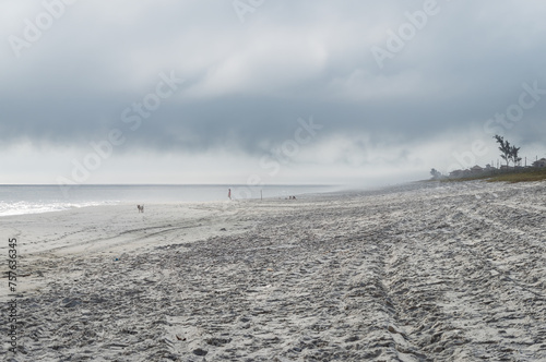 West view of wide and peaceful Praia Seca beach white sands shoreline at Atlantic Ocean blue waters under summer afternoon clouded blue sky in Praia Seca district, Araruama, Rio de Janeiro - Brazil. photo