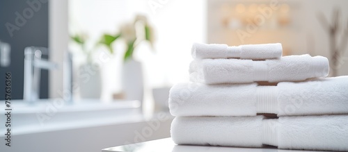 A stack of white towels neatly placed on a wooden counter in a bathroom with hardwood flooring, creating a serene and organized atmosphere