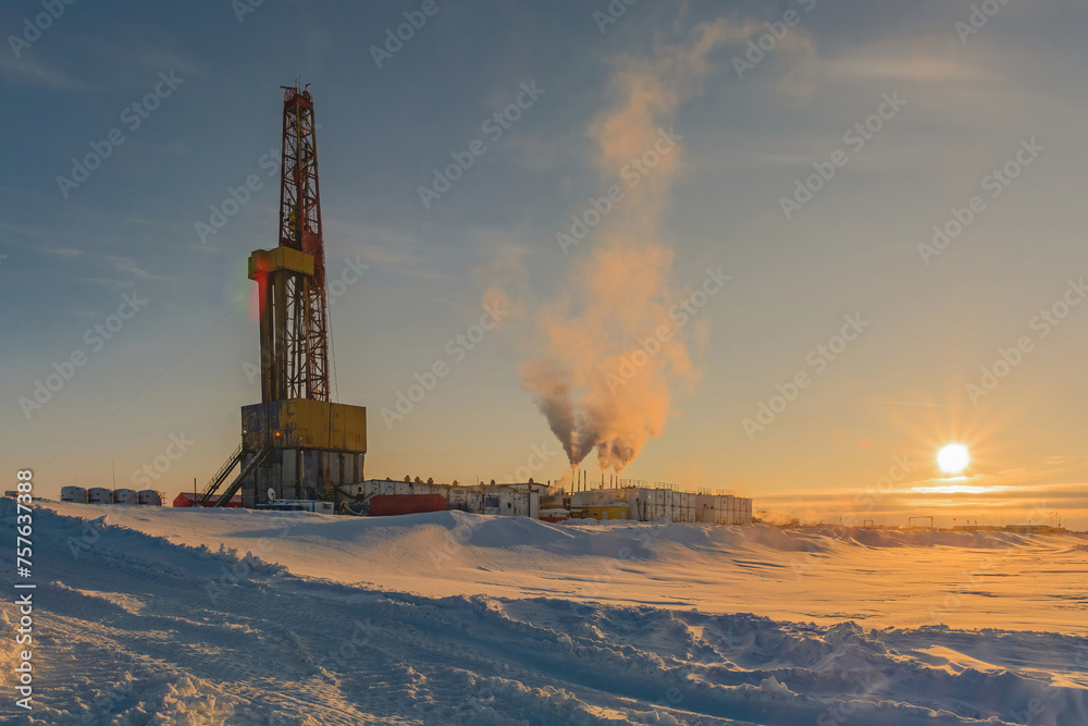 Drilling a deep well for oil and gas production in a northern field. Winter polar day. The low sun illuminates the pure snow of the Arctic desert