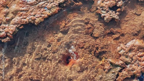 Narzan drinking spring in Ossetia. The bubbling water of a natural mineral spring against the background of a red rocky bottom. The healing water of the Narzan Valley. North Caucasus, Russia. 4K photo