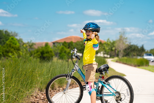 Sporty kid riding bike on a park. Child in safety helmet riding bicycle. Kid learns to ride a bike. Kids on bicycle. Happy child in helmet cycling outdoor. Sports leisure with kids.
