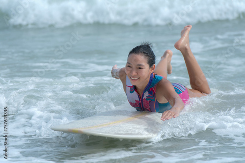 an Asian women Surfboarding in the sea with small waves happily, to people and surfbord concept.