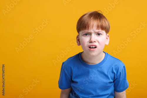 Portrait of surprised little boy on orange background, space for text
