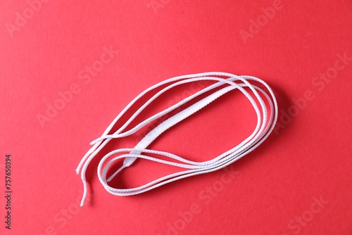 White shoe laces on red background, top view