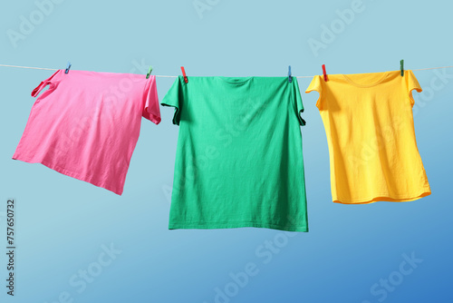 Colorful t-shirts drying on washing line against blue sky