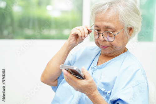 Asian senior woman wearing eyeglasses or vision glasses using a smartphone at home care service. © manassanant