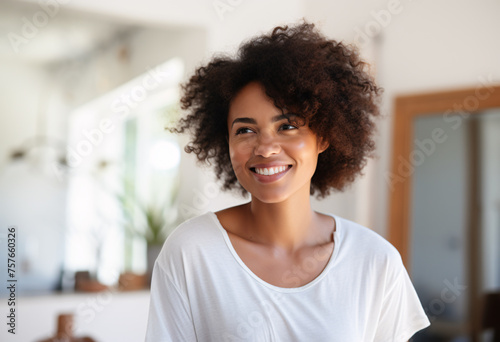 A 20s mix races African European lady in white t-shirt smiling standing in her house in front of vanity with soft focus background 