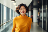 An Asian woman in her late thirties in yellow turtleneck sweater with a smiling face short hair, tall and slender  standing at the office modern interior design with glass walls