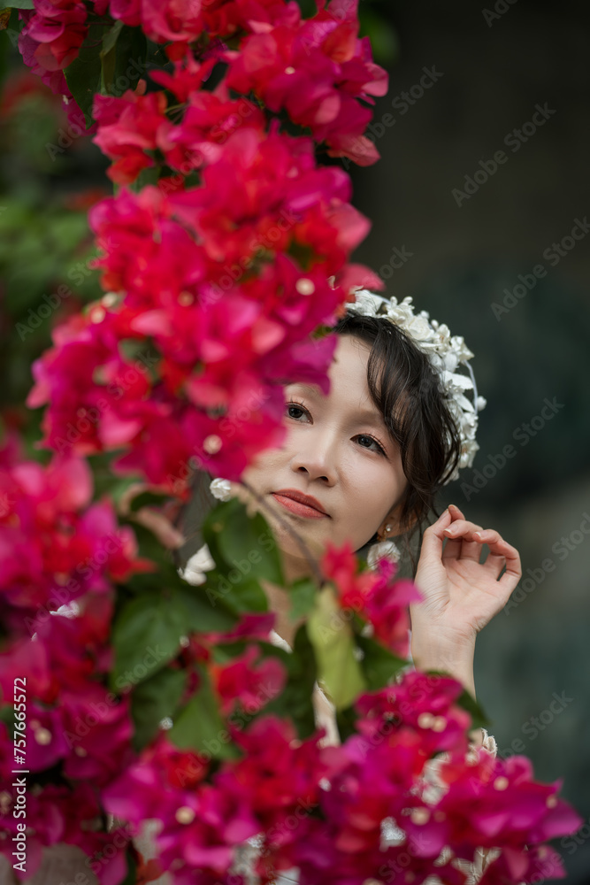 A lady stands with red Bougainvillea, flowers in foreground A lady stands with red Bougainvillea, flowers in foreground